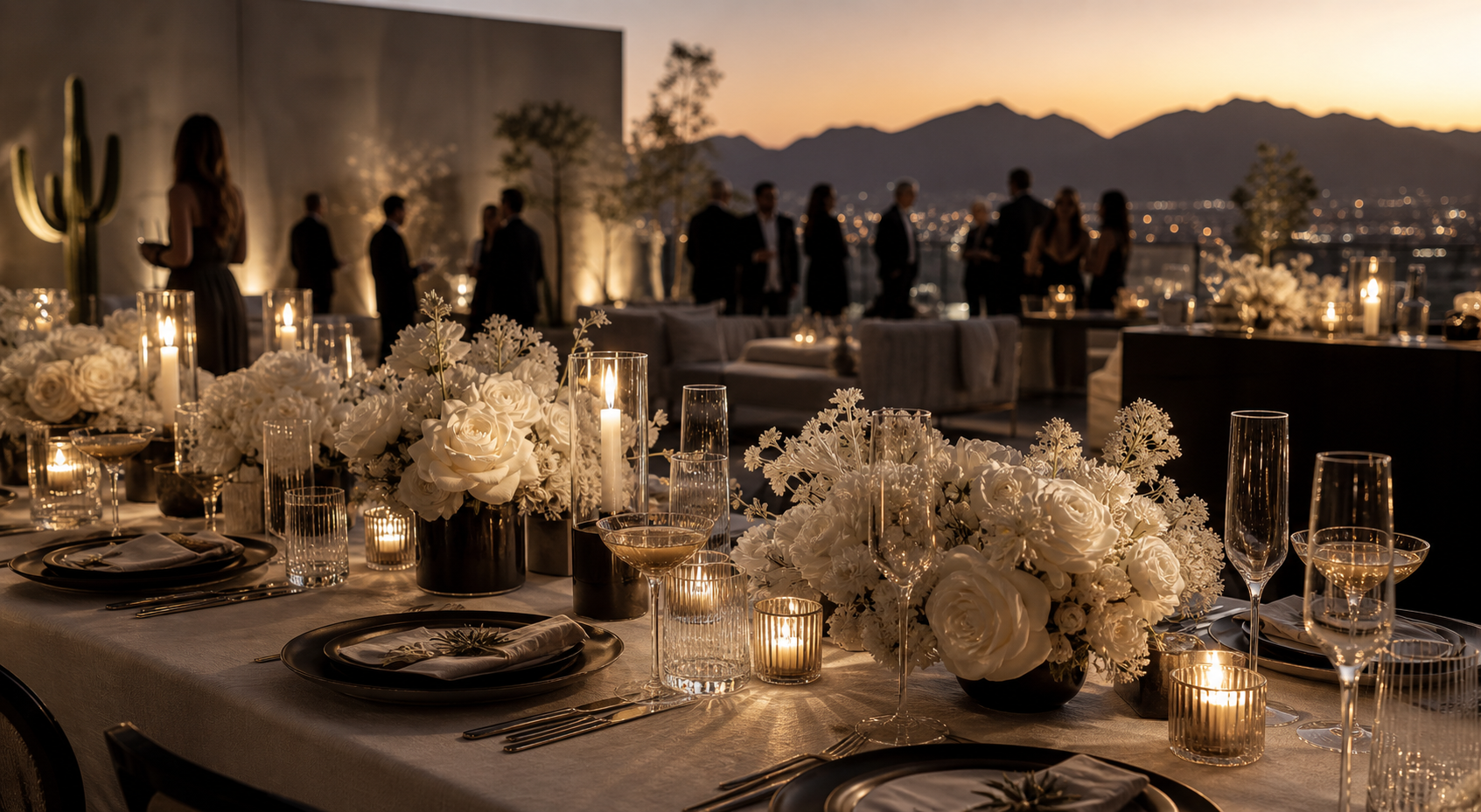 Long candlelit dinner table with cascading white florals and a sunset mountain view.