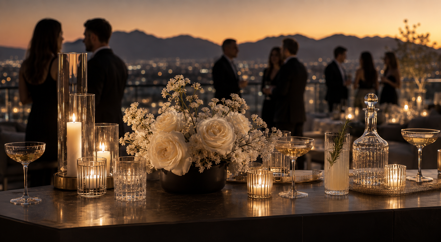 Rooftop cocktail tablescape with white roses, candlelight, and coupe glasses overlooking the city skyline.